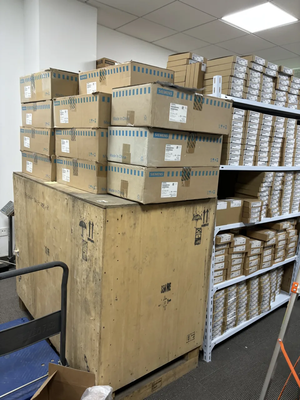 Wooden crate and outer cartons beside warehouse shelving